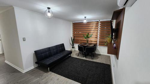 a living room with a black leather couch and a table at Comfortable y central depto 2D 2B with parking in Los Ángeles