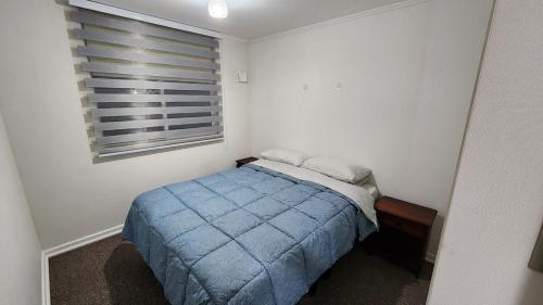 a small bedroom with a blue bed and a window at Comfortable y central depto 2D 2B with parking in Los Ángeles
