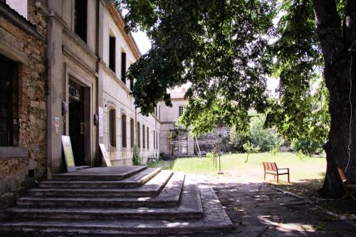 a bench sitting next to a building with a tree at APOSTROPHE Chambres d'Hôtes in Montolieu