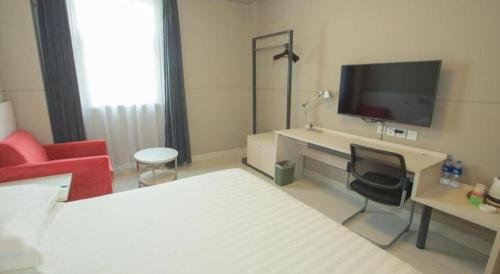 a hotel room with a bed and a chair and a television at Jinjiang Inn Luoyang Wangcheng Park Metro Station in Luoyang