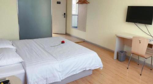 a bedroom with a bed and a desk and a television at 7 Days Inn Hami Baofeng Market in Qumul