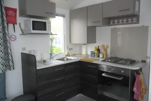une cuisine avec un évier et une cuisinière four supérieur dans l'établissement Mobil home, à La Cotinière