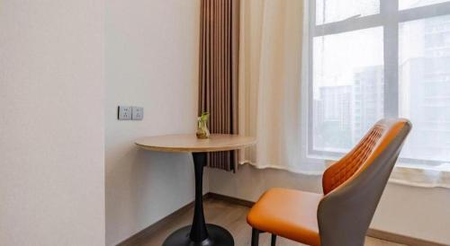 a table and a chair in a room with a window at GreenTree Alliance Anhui Hefei South Passenger Station South High Speed Railway Station Hotel in Hefei