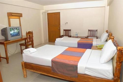 a hotel room with two beds and a television at Submukda Grand Hotel in Mukdahan