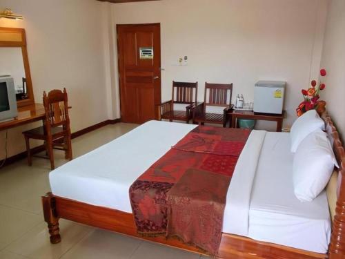 a bedroom with a large bed with a desk and chairs at Submukda Grand Hotel in Mukdahan