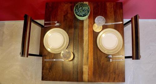 a wooden table with two plates and a plant on it at Theory9 Premium Service Apartments Khar in Mumbai