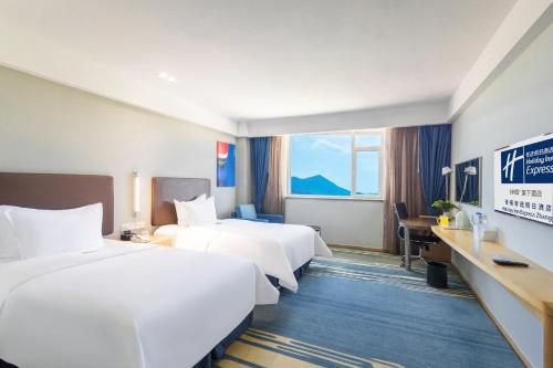 a hotel room with two beds and a desk at Holiday Inn Express Zhangye by IHG in Zhangye