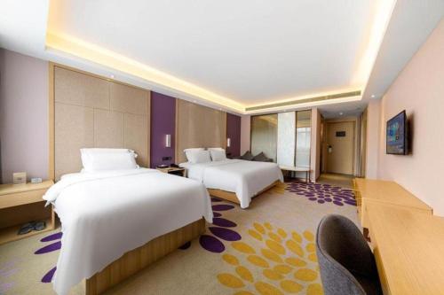 a hotel room with two beds and a desk at Lavande Hotels· Guizhou Anshun Xi Railway Station in Anshun