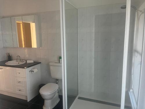 a white bathroom with a toilet and a shower at Bella Casa Geelong in Lovely Banks