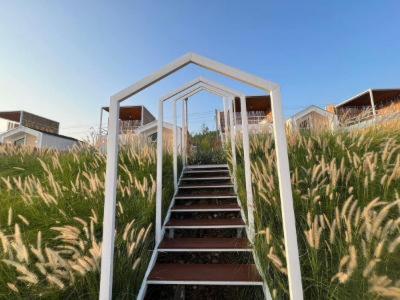 a stairway leading up to a field of tall grass at Nordic Hills Kanchanaburi in Ban Chek