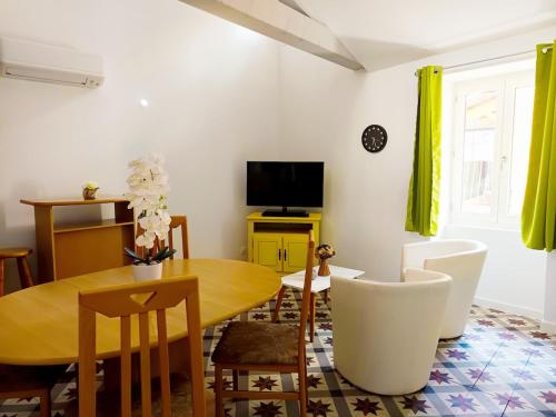 a dining room with a table and chairs and a television at L'écrin de Sisteron - lac, centre-ville et parking in Sisteron