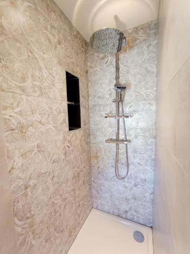 La salle de bains est pourvue d'une douche et d'un mur en pierre. dans l'établissement L'écrin de Sisteron - lac, centre-ville et parking, à Sisteron