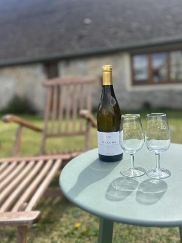 a bottle of wine sitting on a table with two wine glasses at Maison Belles Pierres in Montagny-lès-Beaune