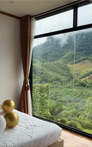 a bedroom with a large window with a view of a mountain at Camping phutajoy Khaosok แคมป์ปิ้งภูตาจ้อยเขาศก in Ban Thung Lang Tham
