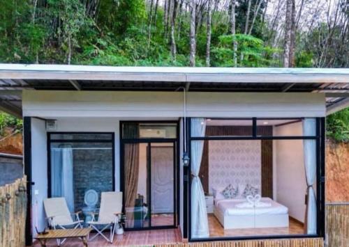a small house with a bed and sliding glass doors at Camping phutajoy Khaosok แคมป์ปิ้งภูตาจ้อยเขาศก in Ban Thung Lang Tham
