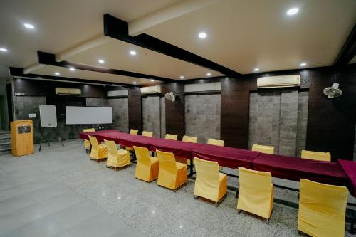 a conference room with a long table and yellow chairs at Hotel Jinendra Inn in Jaipur