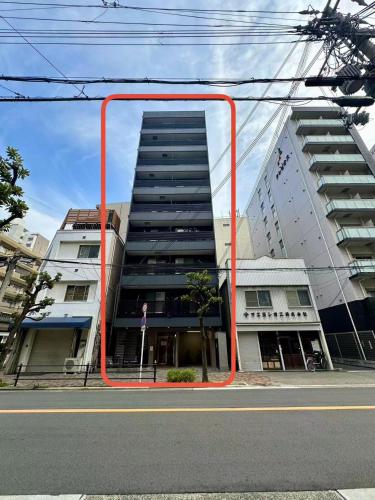 a tall building with an orange frame on a street at JOJO TThouse in Osaka