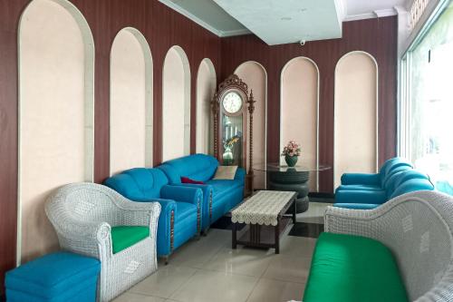 a waiting room with blue chairs and a clock at RedDoorz Hotel Baaraka near Living World in Pekanbaru