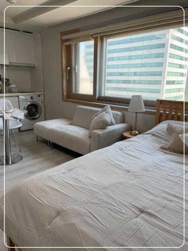 a bedroom with a large white bed and a couch at Gangnam Cozy home 7 min to subway in Seoul