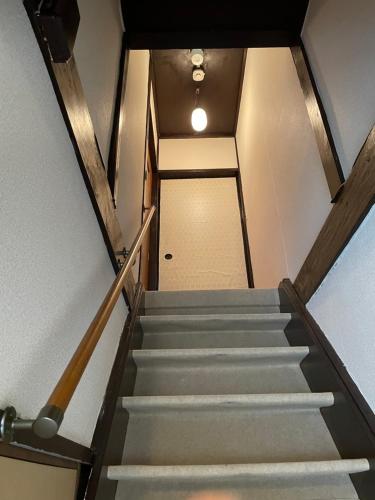 a stairway leading up to a hallway with a white door at サニーサイドホステル1号館 in Uji