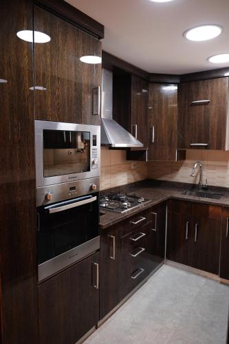 a kitchen with wooden cabinets and a stove top oven at Luxury 1BR Near the Airport in Cairo