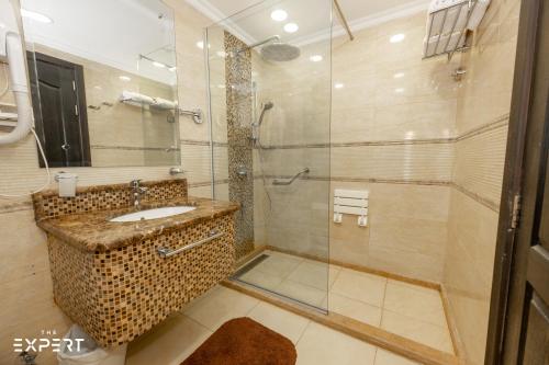 a bathroom with a glass shower and a sink at Luxury 1BR Near the Airport in Cairo