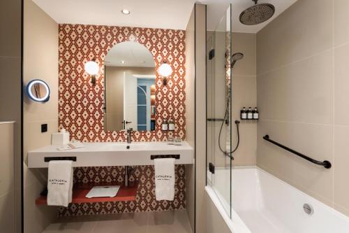 a bathroom with a sink and a mirror and a tub at Catalonia Plaza España Hotel & Spa in Madrid
