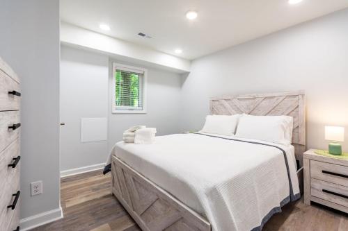 Un dormitorio blanco con una cama grande y una ventana. en Modern Basement Suite, 2BR Sofa Bed, Parking, en Greensboro
