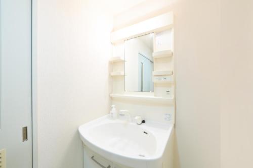 a white bathroom with a sink and a mirror at Residence Hotel KABUTO in Sapporo