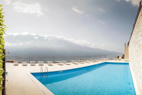 Una piscina con sillas y montañas al fondo. en La Quiete 07 lake view Apartment by Gardadomusmea, en Tremosine Sul Garda