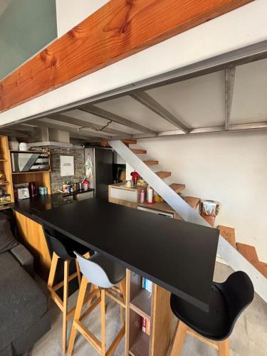 une cuisine loft avec un comptoir noir et des chaises dans l'établissement Appartement Centre ville, à Nice