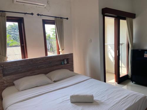een slaapkamer met een groot wit bed met een houten hoofdeinde bij Sanur Base Apartment in Denpasar