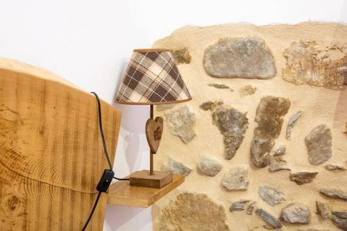 a lamp sitting next to a wall with rocks at C'era una volta una Panetteria in Demonte