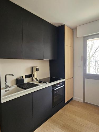 - une cuisine avec des placards noirs et un évier dans l'établissement Annecy centre , Vue lac, ascenseur 4 pers, à Annecy