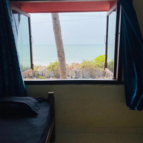 a room with a window with a view of the ocean at Kaustubha beach villa in Udupi