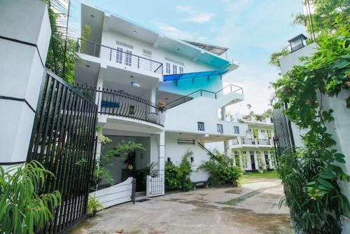 a large white building with a black fence at Tropical Breeze Negombo in Negombo