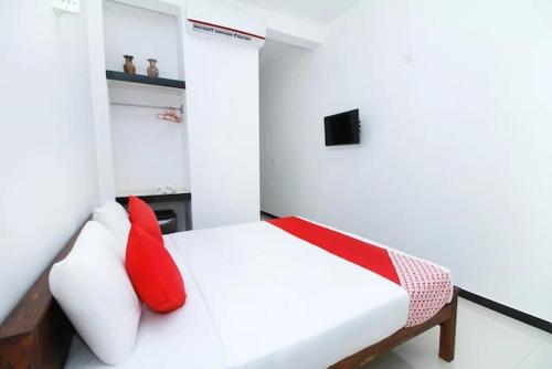 a bedroom with a white bed with red pillows at Tropical Breeze Negombo in Negombo