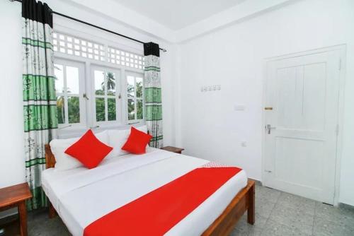 a bedroom with a large white bed with red pillows at Tropical Breeze Negombo in Negombo