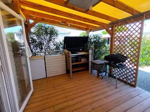 une terrasse couverte avec une télévision et une table dans l'établissement Logis de l'étangs, à Fréjus