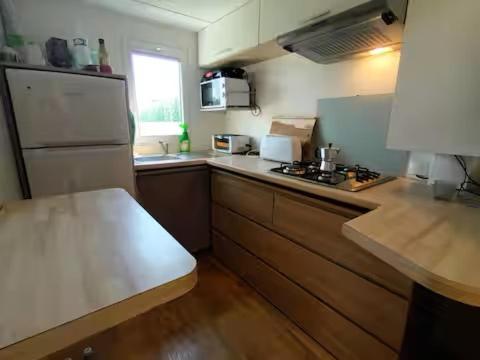 La cuisine est équipée d'un réfrigérateur blanc et de placards en bois. dans l'établissement Logis de l'étangs, à Fréjus