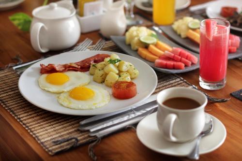 einen Tisch mit einem Frühstücksteller und einer Tasse Kaffee in der Unterkunft Sudha Villa Bali Baik-Baik in Seminyak