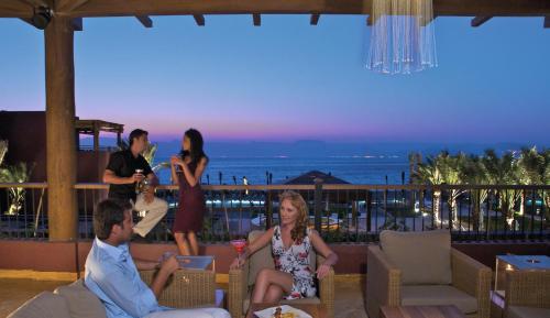 a group of people sitting on a patio at a resort at Mövenpick Resort & Spa Tala Bay Aqaba in Aqaba