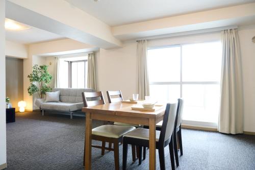 a dining room with a wooden table and chairs at Residence Hotel KABUTO in Sapporo