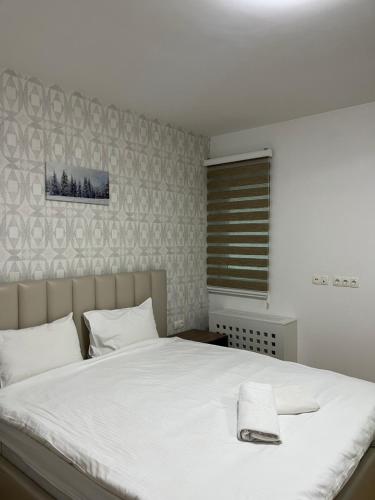 a bedroom with a white bed with a towel on it at Ilidža Tower Sapphire Suites in Sarajevo