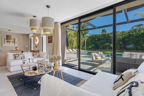 Elle comprend un salon doté d'un mobilier blanc et de grandes fenêtres. dans l'établissement Villa Iris, à Saint-Tropez