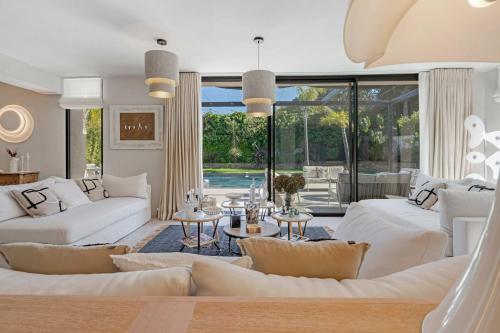 Il comprend un salon doté d'un mobilier blanc et d'une piscine. dans l'établissement Villa Iris, à Saint-Tropez