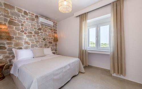 a bedroom with a bed and a stone wall at Muca Houses in Triovasálos