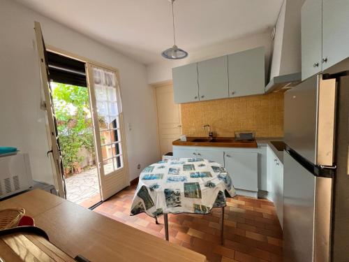 une cuisine avec des armoires blanches et une table à l'intérieur dans l'établissement VUE MER Maison individuelle 30 m de la plage 4 chambres 10 couchages jardin parking LXRM26, à Portiragnes