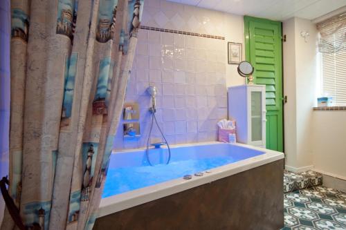 a bathroom with a blue tub with a green door at HR Cottage am Honigbach in Coesfeld