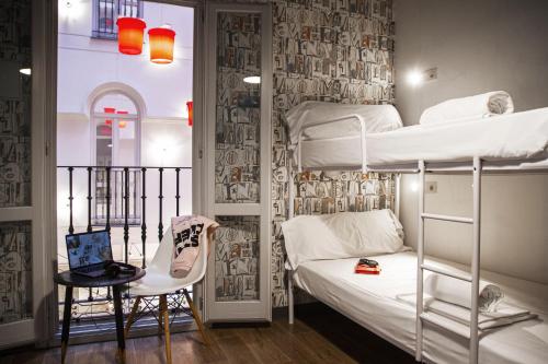 a room with two bunk beds and a laptop on a table at room00 Chueca Hostel in Madrid